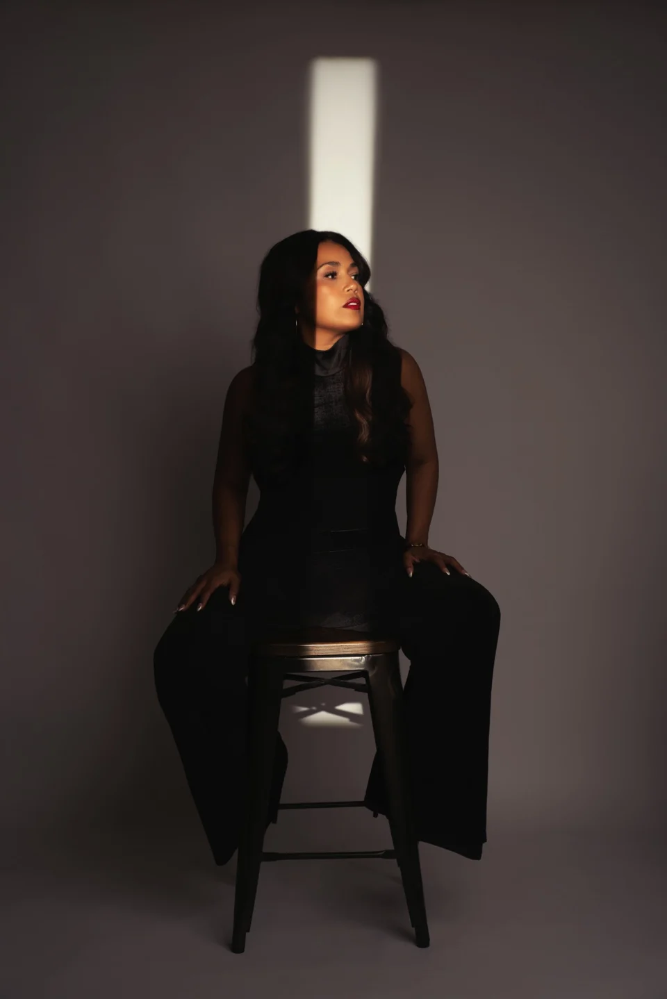 Seated portrait in black with dramatic studio lighting